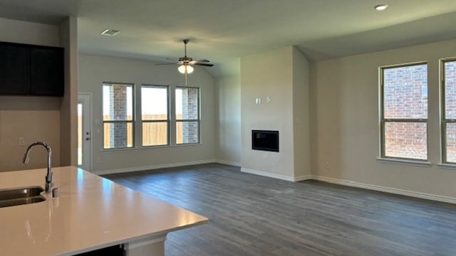 unfurnished living room featuring a wealth of natural light, ceiling fan, and sink