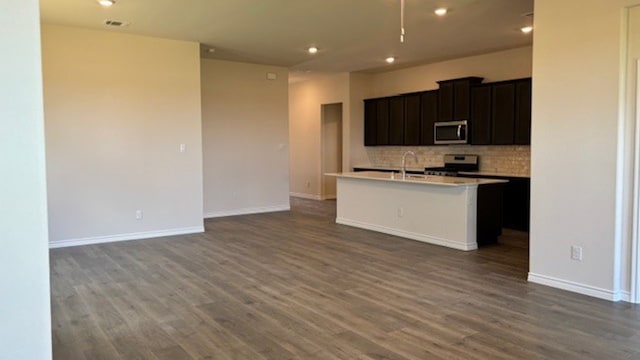 kitchen featuring a kitchen island with sink, stainless steel appliances, sink, decorative backsplash, and hardwood / wood-style flooring