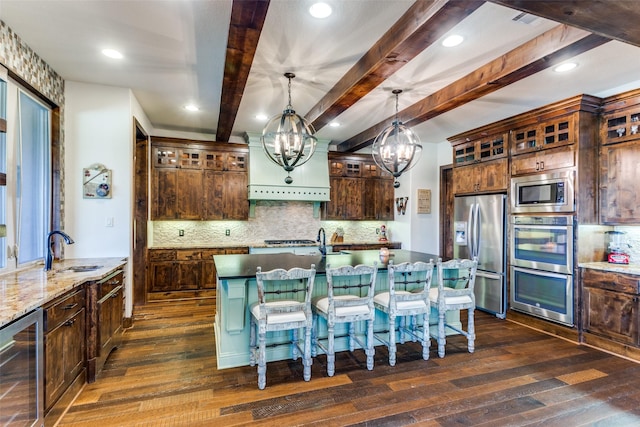 kitchen with sink, hanging light fixtures, beverage cooler, stainless steel appliances, and dark stone countertops