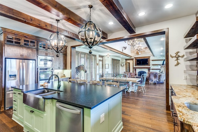 kitchen with green cabinets, dark hardwood / wood-style floors, an island with sink, beamed ceiling, and stainless steel appliances