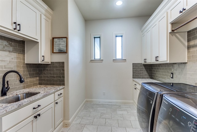 laundry area with cabinets, light tile patterned floors, washing machine and dryer, and sink