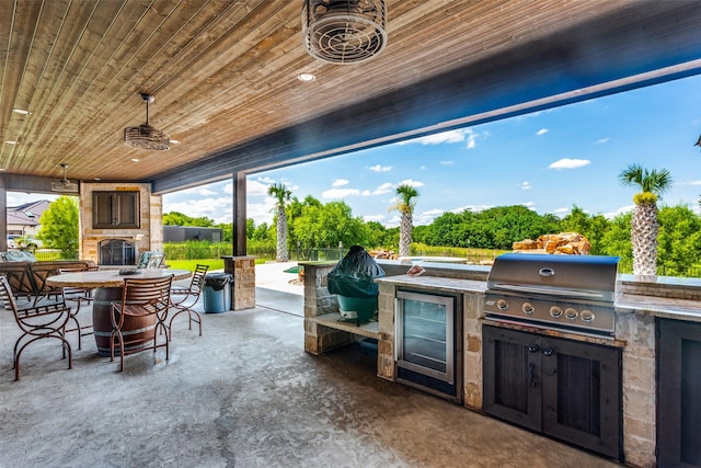 view of patio with grilling area, an outdoor kitchen, and an outdoor stone fireplace