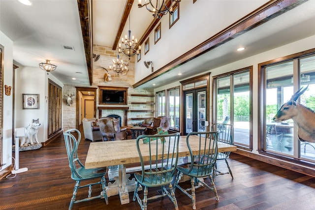 dining space with a large fireplace, french doors, dark hardwood / wood-style flooring, beamed ceiling, and a chandelier