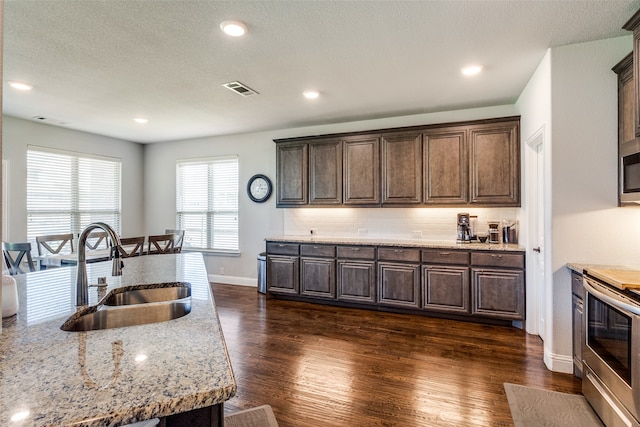 kitchen featuring dark hardwood / wood-style flooring, tasteful backsplash, stainless steel range with electric stovetop, dark brown cabinets, and sink