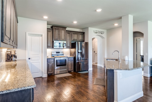 kitchen with light stone countertops, stainless steel appliances, dark hardwood / wood-style floors, and sink