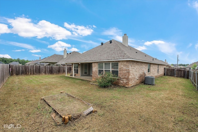 rear view of house featuring cooling unit, a yard, and a patio