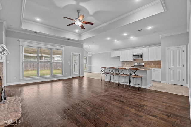 living room featuring a raised ceiling, crown molding, ceiling fan, and light hardwood / wood-style floors