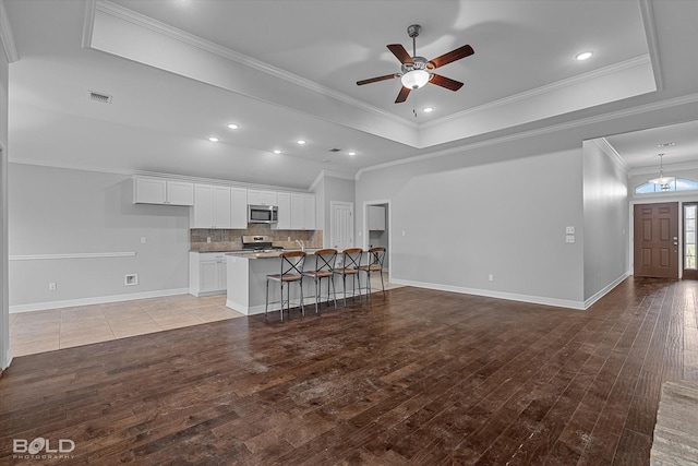 unfurnished living room featuring crown molding, ceiling fan, a tray ceiling, and light hardwood / wood-style flooring