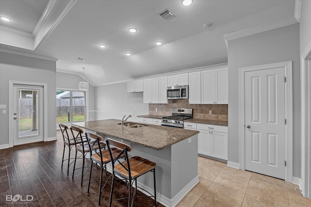 kitchen featuring white cabinetry, a center island with sink, a breakfast bar, and appliances with stainless steel finishes