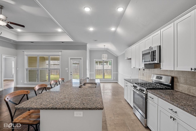 kitchen with stainless steel appliances, an island with sink, white cabinets, and a kitchen breakfast bar