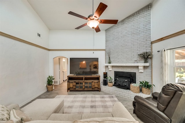 living room featuring ceiling fan, a brick fireplace, high vaulted ceiling, and light hardwood / wood-style floors