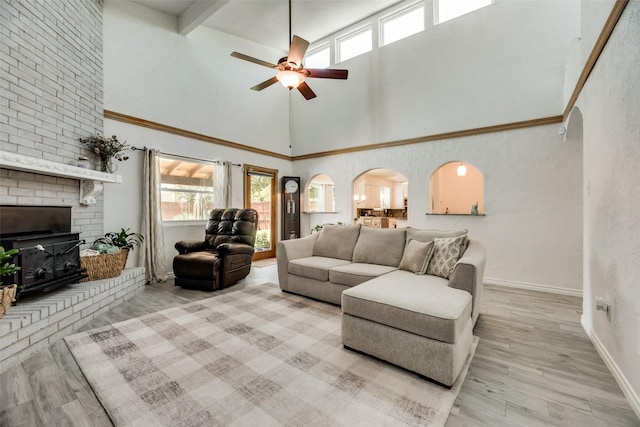 living room featuring a healthy amount of sunlight, a fireplace, ceiling fan, and light hardwood / wood-style flooring