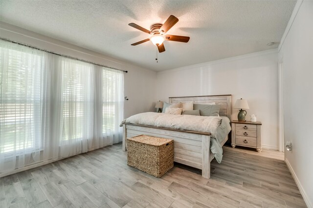 bedroom with ceiling fan, light hardwood / wood-style floors, a textured ceiling, and ornamental molding