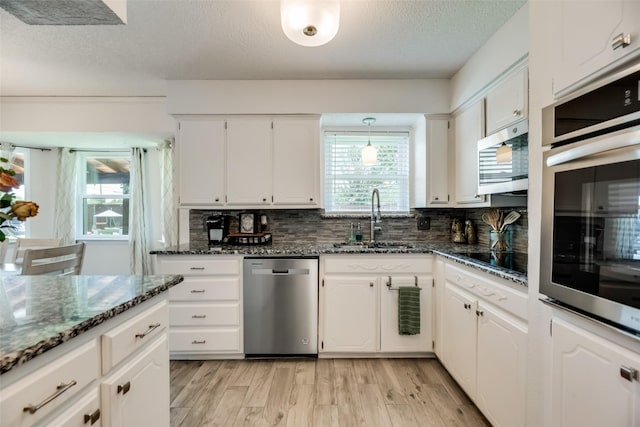 kitchen with stainless steel appliances, sink, dark stone countertops, and white cabinets