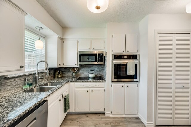 kitchen featuring stainless steel refrigerator, white cabinets, dark stone counters, and a textured ceiling