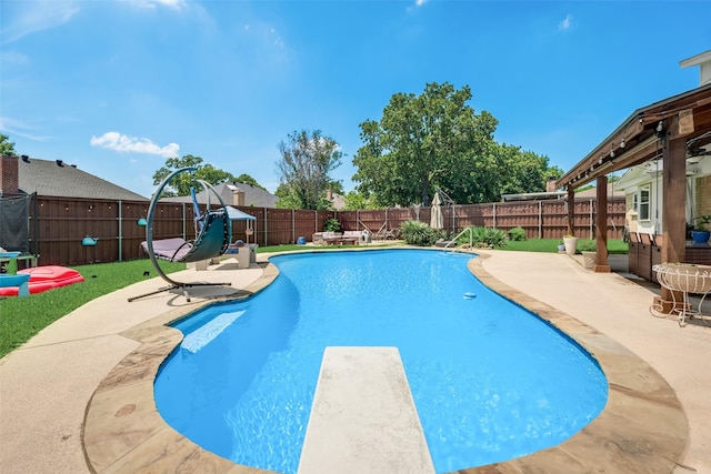 view of pool with a diving board and a patio