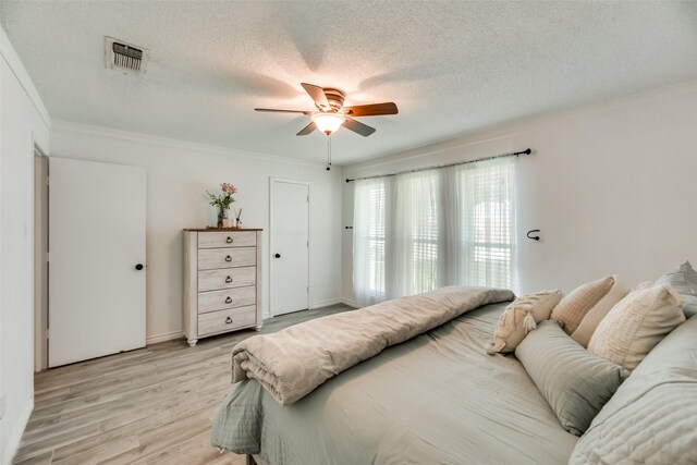 bedroom with ceiling fan, ornamental molding, a textured ceiling, and light hardwood / wood-style flooring