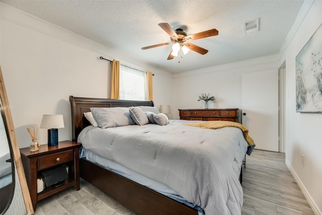 bedroom with ceiling fan, crown molding, a textured ceiling, and light wood-type flooring