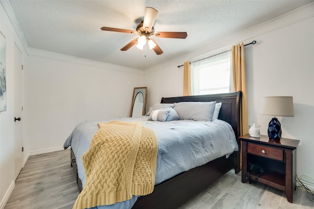 bedroom featuring ceiling fan, light hardwood / wood-style floors, and a textured ceiling