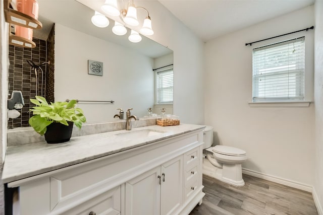 bathroom featuring hardwood / wood-style flooring, tiled shower, vanity, toilet, and a chandelier