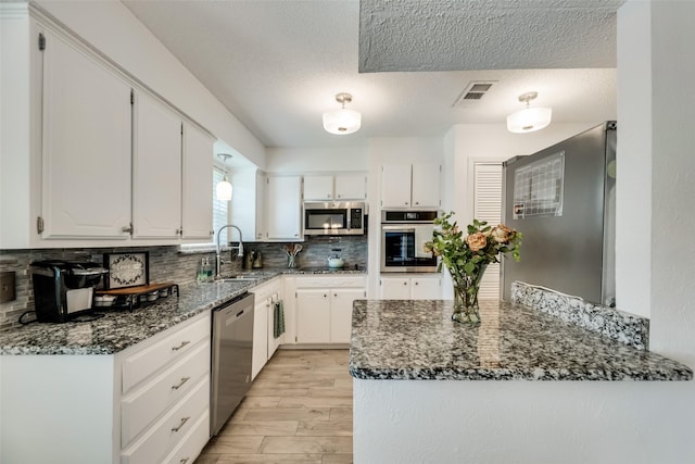 kitchen featuring sink, dark stone counters, white cabinets, and appliances with stainless steel finishes