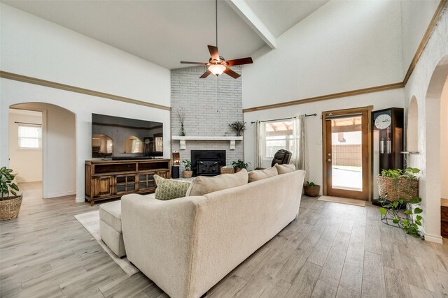 living room featuring ceiling fan, a towering ceiling, and light wood-type flooring