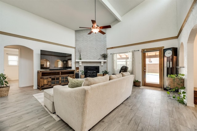 living room with ceiling fan, plenty of natural light, a high ceiling, and light wood-type flooring