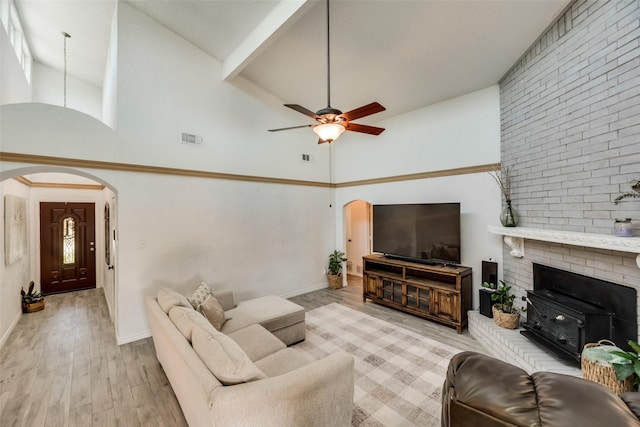 living room with ceiling fan, a towering ceiling, a wealth of natural light, and light hardwood / wood-style floors