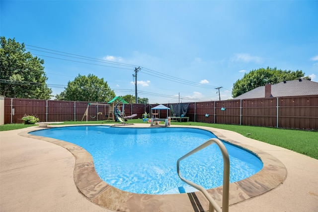 view of pool with a playground, a patio area, and a lawn