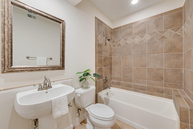 full bathroom featuring sink, tiled shower / bath combo, and toilet