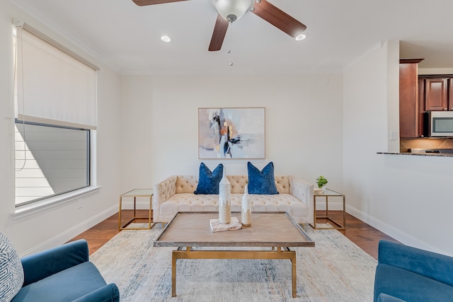 living room with ceiling fan, light wood-type flooring, and crown molding