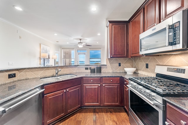 kitchen with sink, tasteful backsplash, light stone counters, light hardwood / wood-style floors, and appliances with stainless steel finishes