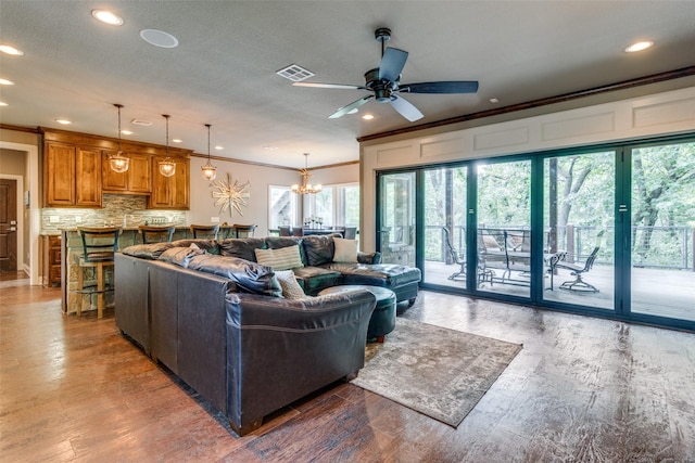 living room with ornamental molding, ceiling fan with notable chandelier, and wood-type flooring