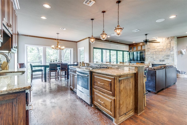 kitchen featuring sink, stainless steel gas stove, a kitchen island, dark hardwood / wood-style flooring, and pendant lighting