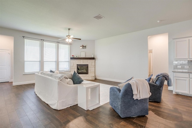 living room with dark hardwood / wood-style flooring, ceiling fan, and a fireplace