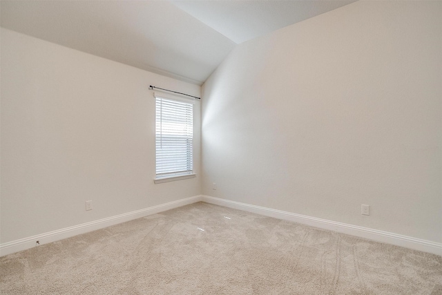 carpeted empty room with lofted ceiling