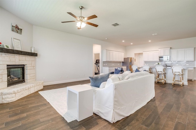 living room featuring a fireplace, dark wood-type flooring, and ceiling fan