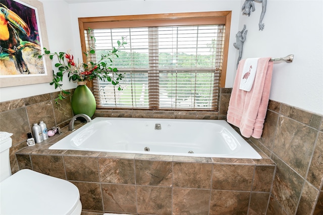 bathroom featuring a relaxing tiled bath, plenty of natural light, and toilet