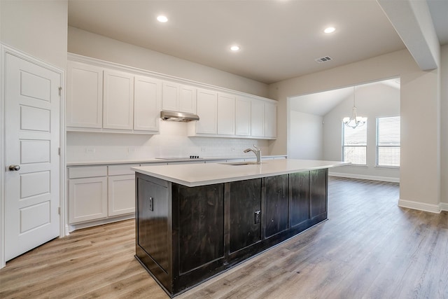 kitchen featuring sink, light hardwood / wood-style flooring, backsplash, a center island with sink, and white cabinets