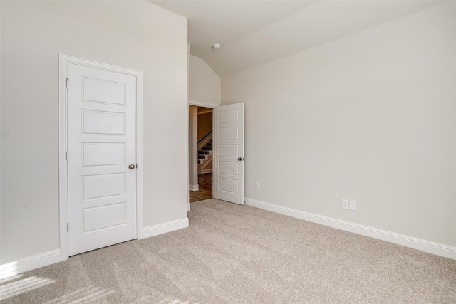 unfurnished bedroom featuring light colored carpet and vaulted ceiling