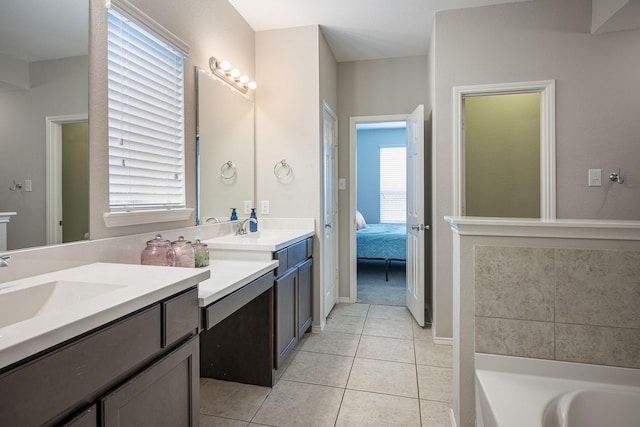 bathroom with a tub to relax in, a wealth of natural light, tile patterned flooring, and vanity