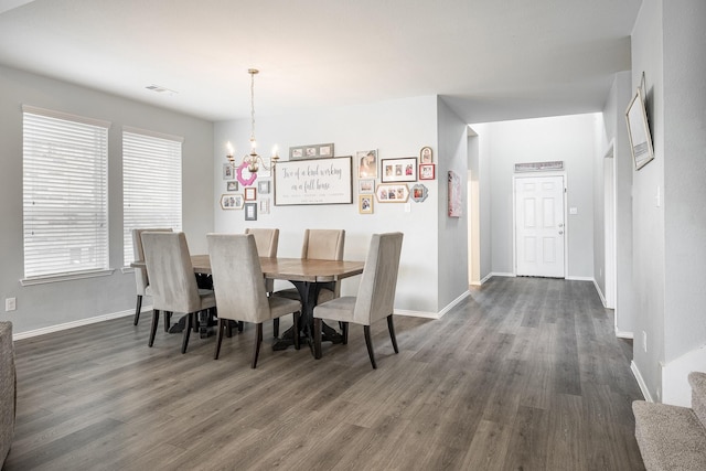 dining area with dark wood-type flooring and an inviting chandelier