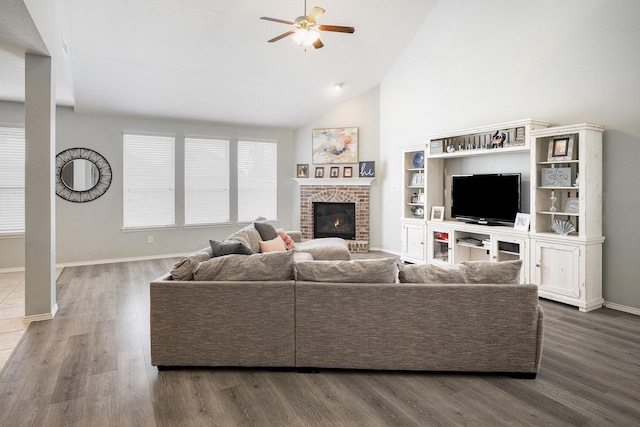 living room featuring high vaulted ceiling, a brick fireplace, ceiling fan, and dark wood-type flooring