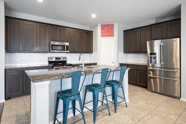 kitchen featuring sink, a center island with sink, dark brown cabinets, and appliances with stainless steel finishes