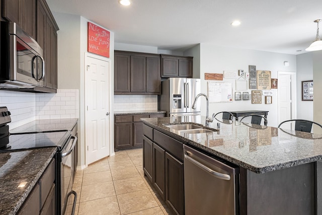 kitchen with backsplash, a center island with sink, sink, appliances with stainless steel finishes, and light tile patterned flooring