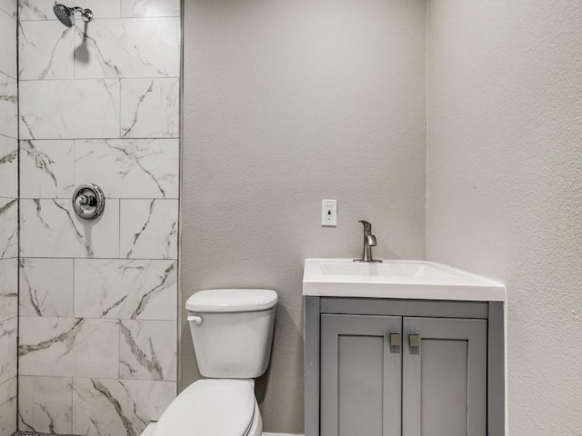 bathroom featuring vanity, toilet, and a tile shower