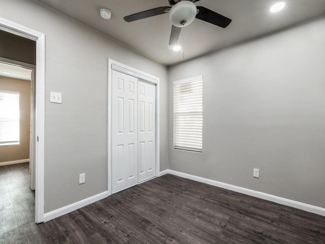 unfurnished bedroom with ceiling fan, dark hardwood / wood-style flooring, and a closet