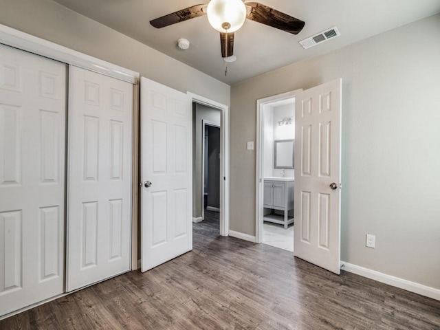 unfurnished bedroom featuring dark hardwood / wood-style flooring, a closet, ceiling fan, and connected bathroom