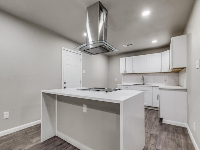 kitchen with cooktop, island range hood, a kitchen island, sink, and white cabinetry