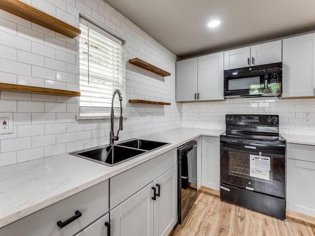 kitchen with white cabinets, sink, light hardwood / wood-style floors, and black appliances